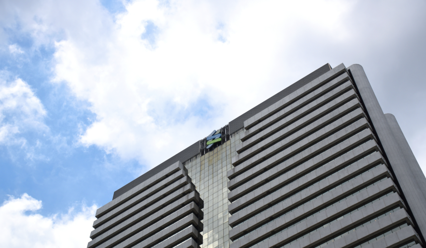 A tall, modern office building with a blue sky and white clouds in the background