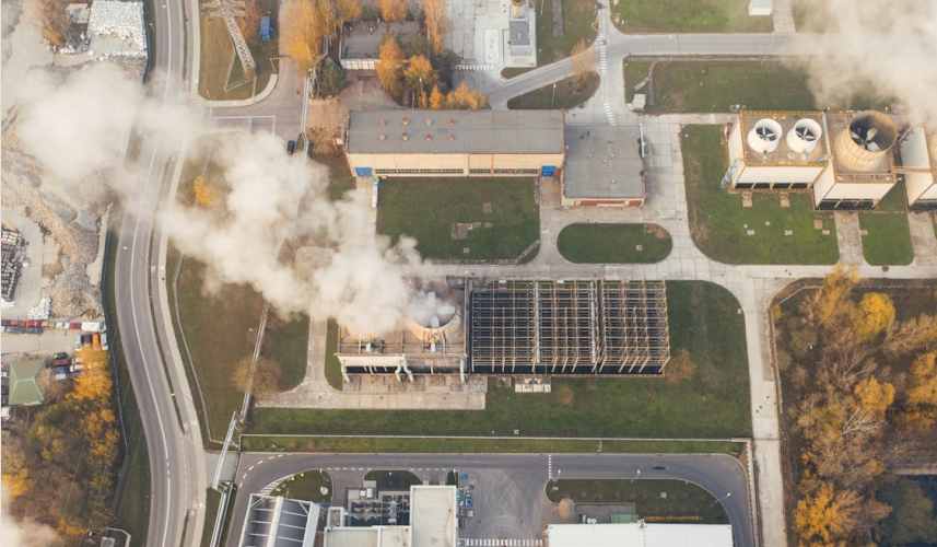 A factory from above, with smoke billowing from its smokestacks.